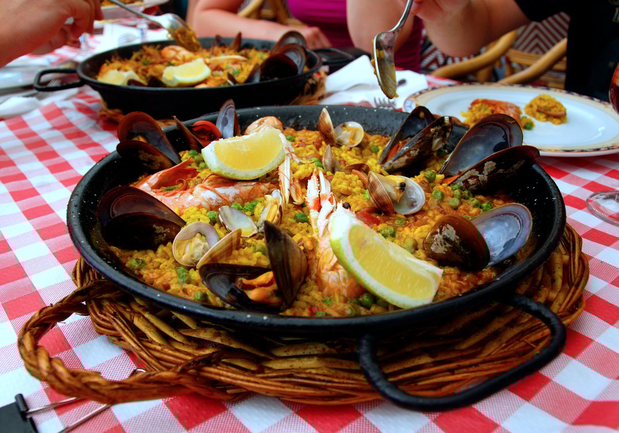 Traditional Spanish seafood paella served in a pan with lemon wedges, enjoyed by diners at a restaurant.