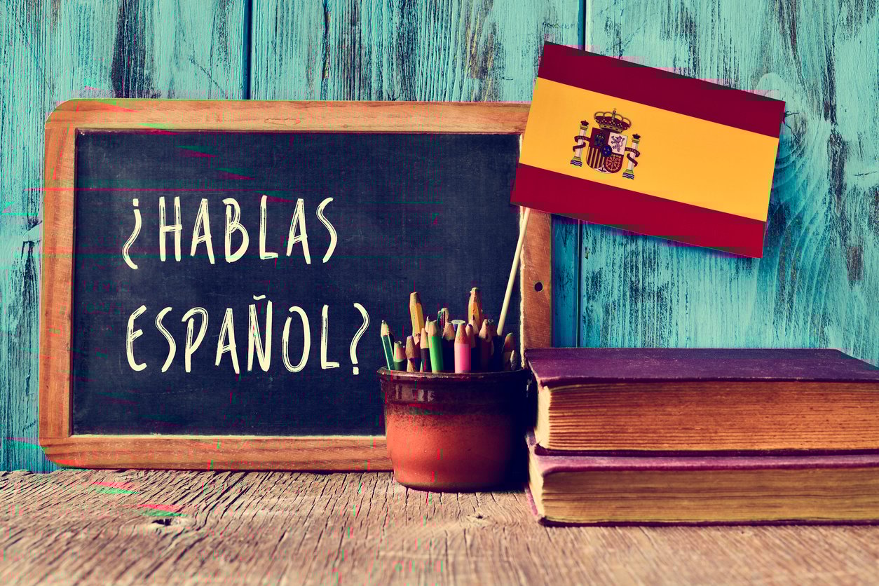 Chalkboard with the text '¿Hablas Español?' next to Spanish flag and books.