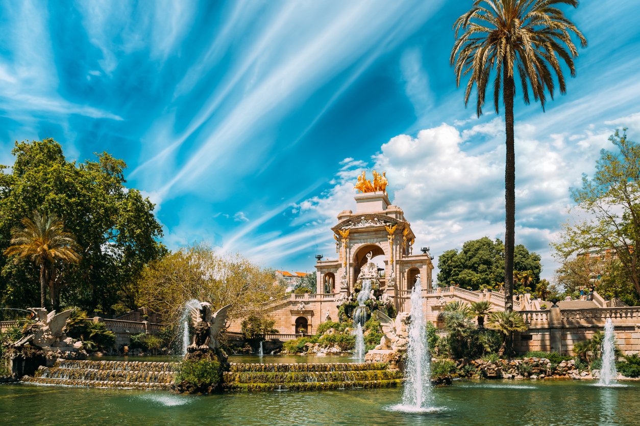 The Cascada Monumental fountain in Ciutadella Park, Barcelona, surrounded by lush greenery under a vibrant blue sky.